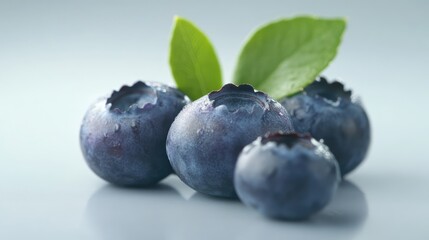Aufkleber - Fresh blueberries with green leaves on a soft background showcasing natural textures and details of the fruit. Ideal for food-related themes.