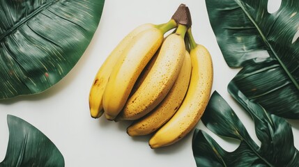 Aufkleber - Ripe bananas arranged on a light background surrounded by tropical green leaves for a fresh and vibrant display.