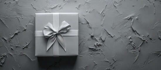Poster - Elegant gray gift box with ribbon and bow arranged on textured background showcasing flat lay design and ample copy space for text.