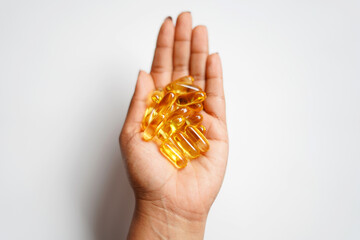 Wall Mural - hand holding golden color cod liver capsules