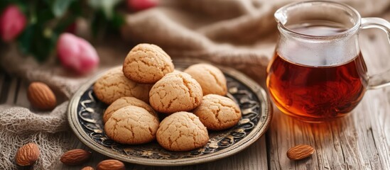 Aufkleber - Almond cookies served with tea on a decorated plate with floral accents and rustic wood background