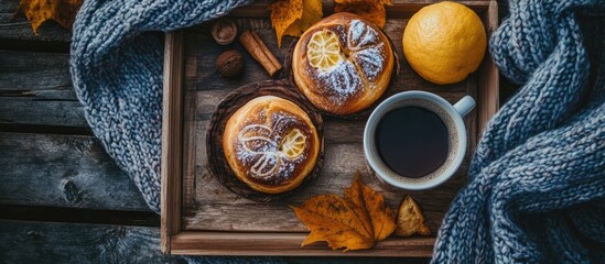 Aufkleber - Cozy breakfast scene with homemade lemon buns, hot coffee, and autumn leaves on a wooden tray with a warm knitted background
