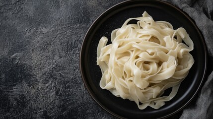 Poster - Homemade Fresh Noodles Twisted on a Black Plate with Dark Textured Background