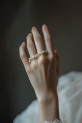 Aufkleber - Hand wearing pearl ring against dark background.