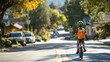 © xu - A young boy wearing a safety helmet rides his bike, carrying a bright orange school backpack, while crossing a quiet street on a sunny day, emphasizing child safety