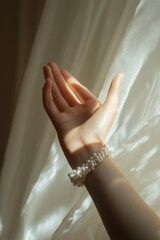 Aufkleber - Hand with pearl bracelet against draped fabric.