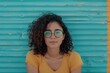 © darshika - Content adult overweight female in eyewear curly hair against ribbed wall in daytime