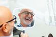 © Antonio Gravante - Senior man admiring his new smile in dental clinic mirror