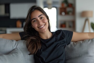 Hispanic woman smiling on couch in black t shirt at home