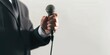 © vefimov - Man in a suit holding a microphone. The microphone is black and white. The man is wearing a suit and tie