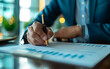 © Vadim - A man is writing with a pen on a piece of paper. Concept of professionalism and focus, as the man is dressed in a suit and he is working on important documents