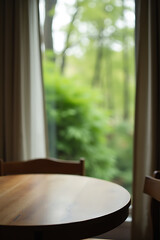 Poster - A wooden table sits atop a blurred curtain with a view of greenery through a window surrounded by trees in a garden setting._00002_