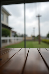 Poster - A wooden table has a blurred glass window view of a nearby building in the distant outdoor scenery._00003_