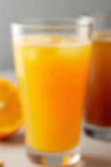 Poster - A brightly colored glass of orange juice is placed in front of a blurred background of various other fruit drinks._00001_