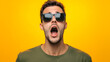 © mahamad - A young man wearing sunglasses, surprised and shocked against an isolated background.