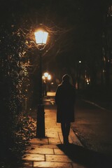 Poster - Nighttime stroll, lone figure, streetlight glow, shadows.