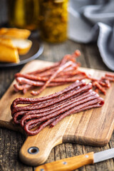 Wall Mural - Smoked kabanos. Mini dried thin sausages on cutting board on wooden table.