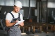 © Serhii - Portrait of a young worker in a hard hat at a large metalworking factory. Shiftman on the warehouse of finished products