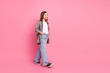 © deagreez - Smiling young girl in a trendy outfit walking against a bright pink background