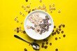 © Andrew Kornylak - A mix of chocolate and plain cheerios floating in milk in a plain white bowl and scattered on a yellow background. A spoon sits beside the bowl.