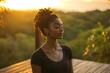 © gankevstock - Black young woman practicing yoga on a wooden deck at sunset