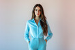© angelo lano - Full length portrait of a beautiful girl in her 20s wearing a light blue blouse and light blue trousers in casual style, standing against a light solid color background