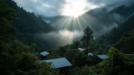 Wall Mural - sunlight breaks through clouds over a misty mountain valley with rustic cabins in the foreground