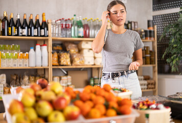 Wall Mural - Young woman buyer forgot what she wanted to buy at grocery store