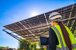 © ultramansk - Engineer in safety vest and helmet pointing towards a solar powered carport, illustrating eco-friendly innovation in parking infrastructure. Solar panels provide shade and sustainable energy.