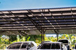 © ultramansk - Engineer in safety vest and helmet pointing towards a solar powered carport, illustrating eco-friendly innovation in parking infrastructure. Solar panels provide shade and sustainable energy.