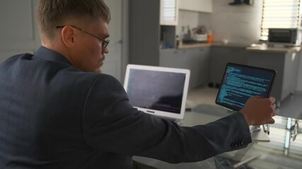 Developer in suit reviews code on laptop in minimalist living room.