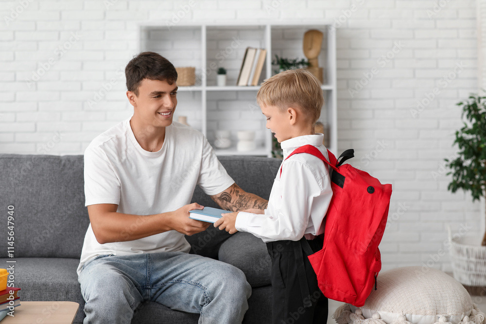 Father giving books to his little son at home