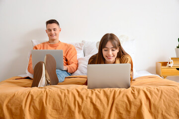 Canvas Print - Young couple using laptops in bedroom