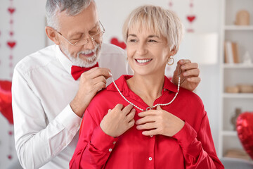 Poster - Mature man greeting his happy wife with pearl necklace at home. Valentine's Day celebration