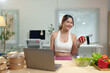© crizzystudio - Young Asian woman live chatting, video calling on laptop computer, how to lose weight with diet. Introducing useful fruits and vegetables Lifestyle Influencer Healthy concept, lifestyle.