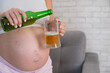 © Михаил Решетников - Faceless pregnant woman pouring beer into a glass.