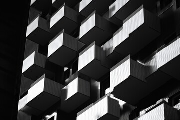 Fototapete - A black and white photograph showcasing the abstract design of a building's balconies, capturing the interplay of light and shadow in a minimalist style.