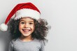 © Alla - A young child smiling while wearing a festive Santa hat, perfect for holiday season and family celebrations