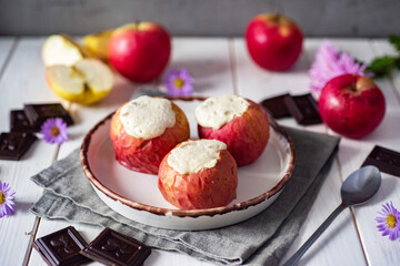 Wall Mural - Baked apples with cottage cheese and raisins on a white plate on a white table. A sweet breakfast. Close-up