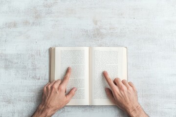 Poster - Hands Pointing at Open Book Pages on Textured Surface in Soft Light
