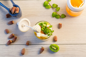 Wall Mural - homemade yogurt with kiwi, honey and nuts in a glass on a wooden table