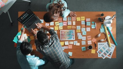 Sticker - Top down view of business team with casual outfit looking laptop screen and sharing idea. Aerial view of manager working and checking color palette at table with sticky notes and headphone. Symposium.