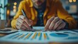 © nimaxs - A focused individual analyzes data on a sheet with graphs and charts, using a pen, in a bright, modern workspace.