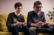 © Lomb - Father and son concentrating on retro gaming at home during family time