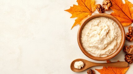 Wall Mural - A bowl of cottage cheese with walnuts and maple leaves on a white background