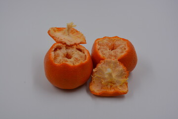 Wall Mural - Healthy, wholesome food, fruits. 
Small slices of orange tangerine are located on a white matte background. Two not whole orange tangerines.