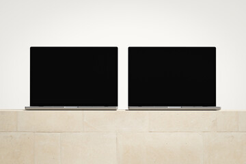 Wall Mural - two opened laptops with a blank screen on the light brick podium