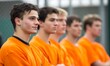 © Sebelas Studio - A group of young men in orange uniforms standing in line.
