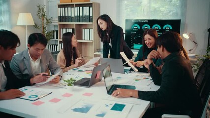 Wall Mural - Young asian woman working late in a home office, sitting at a desk and typing on a computer. Focused on tasks, she manages paperwork and analyzes financial data under the glow of the screen