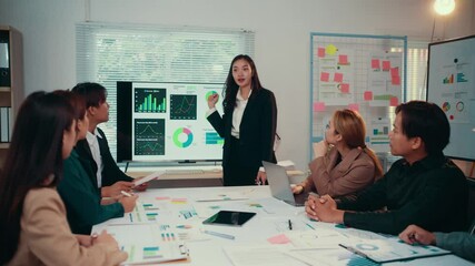 Wall Mural - Confident businesswoman using large monitor to present financial charts and graphs during a corporate meeting with diverse colleagues in modern office space